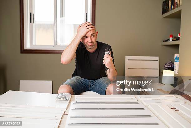 man assembling furniture at home, looking desperate - frustrated workman stock pictures, royalty-free photos & images