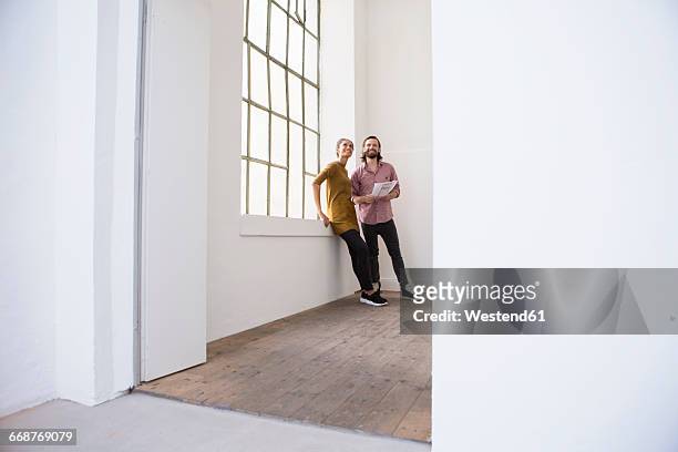 young couple in new home looking around - new house imagens e fotografias de stock