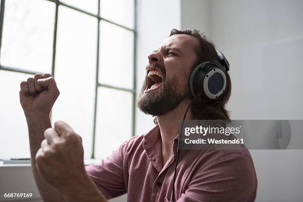 man with headphones singing to music - singing inside stock-fotos und bilder