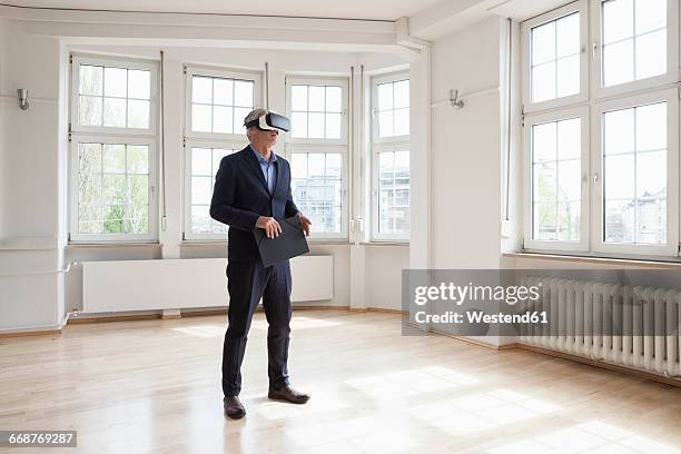 real estate agent wearing virtual reality glasses in empty apartment - virtualitytrend stock pictures, royalty-free photos & images