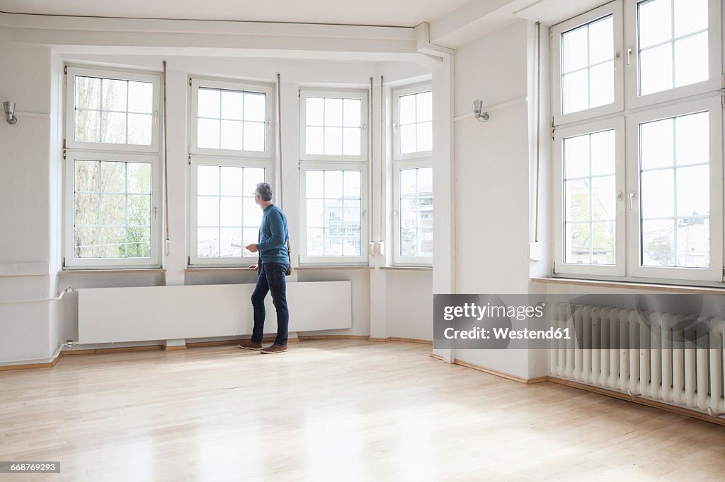 Man looking out of window in empty apartment