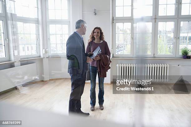 real estate agent talking to client in empty apartment - visie photos et images de collection