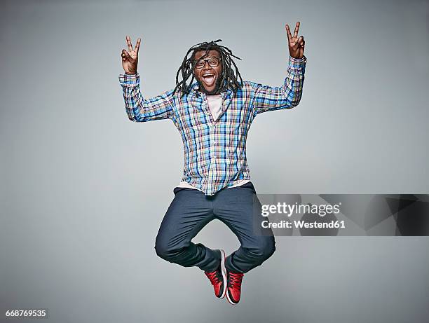 screaming man with dreadlocks jumping in the air while showing victory signs - peace sign guy stock pictures, royalty-free photos & images