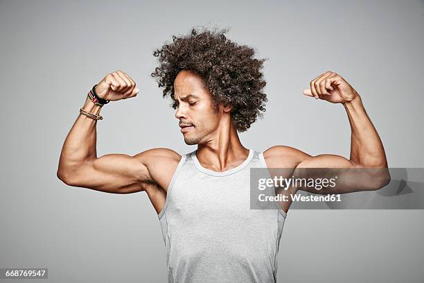 portrait of man with afro flexing his muscles - bicep stock-fotos und bilder