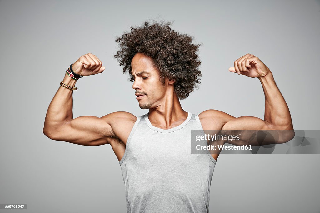 Portrait of man with afro flexing his muscles