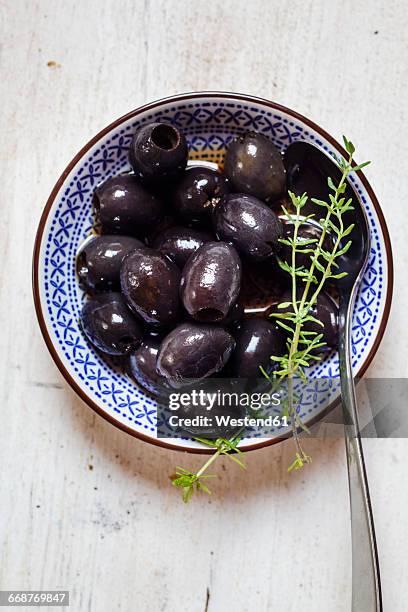 black olives in bowl with thyme - black olive stockfoto's en -beelden