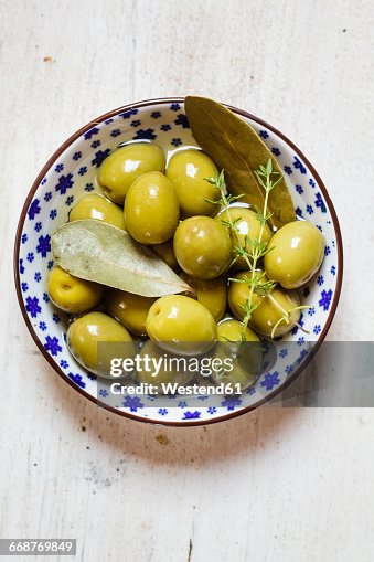 Green olives in bowl with thyme and bay leaf Green olives in bowl with thyme and bay leaf