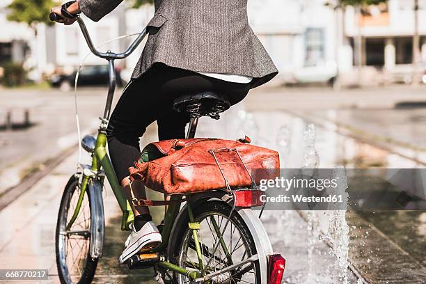 back view of woman riding bicycle, partial view - folding bike stockfoto's en -beelden