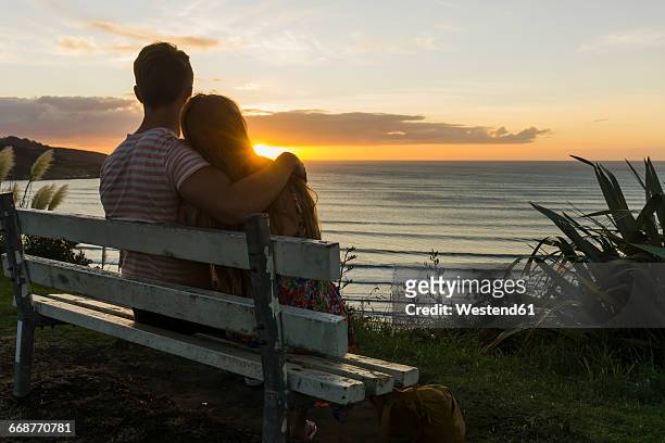couple in love sitting on bench looking at sunset - romantic sky stock pictures, royalty-free photos & images
