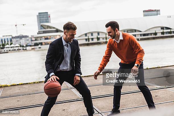 two colleagues playing basketball after work - businessman after work stock-fotos und bilder