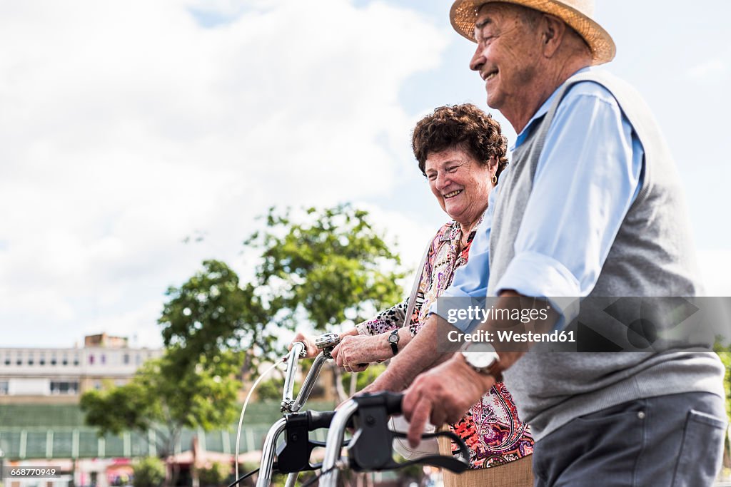 Happy senior couple with bicycle and wheeled walker