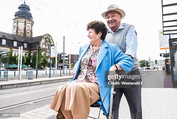 germany, mannheim, happy senior couple with wheeled walker waiting at station - rollator stock-fotos und bilder
