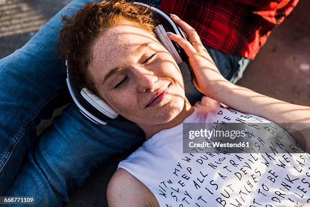 young woman with headphones lying on boyfriend's lap - hearing 個照片及圖片檔