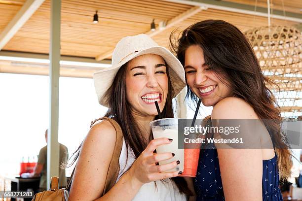 two young woman drinking cocktails in beach bar - girls night out stockfoto's en -beelden