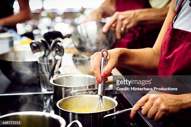 hands stiring sauce in a hot pan - cookery class stock-fotos und bilder