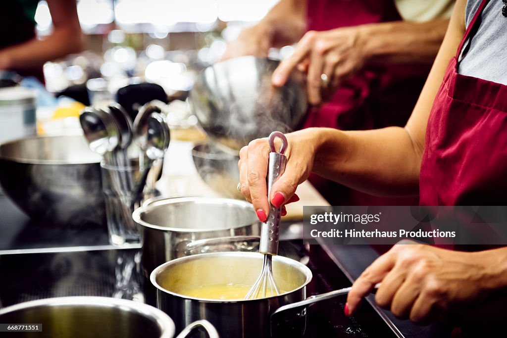 Hands stiring sauce in a hot pan