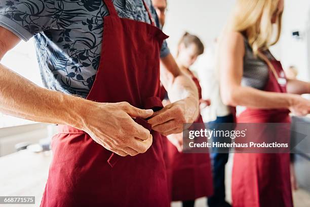 tying an apron in a cooking class - grembiule foto e immagini stock