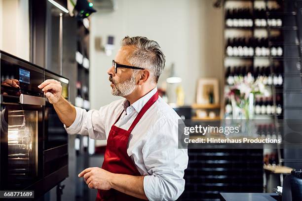 mature man on a modern stove - kitchen apron stock pictures, royalty-free photos & images