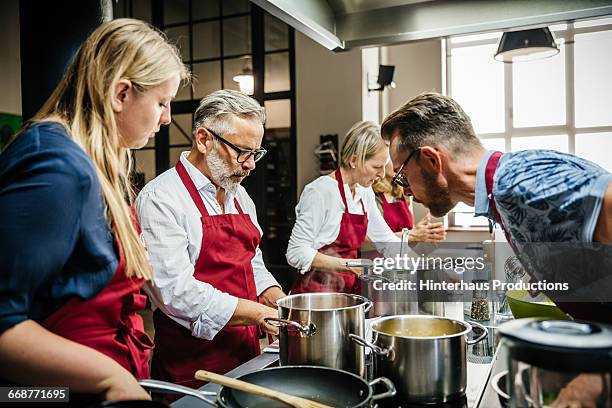 cooking class preparing dinner together - kochschürze stock-fotos und bilder