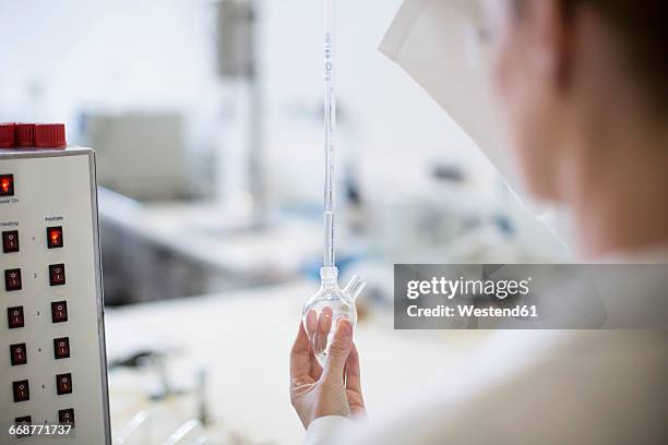 scientist in lab holding round-bottom flask - glaskolben stock-fotos und bilder