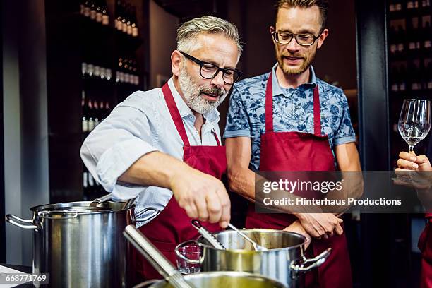 mature men in a cooking class having fun - kochschürze stock-fotos und bilder