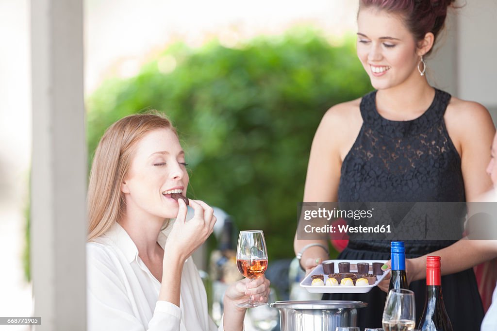 Woman enjoying wine and chocolates served in restaurant