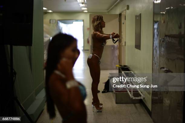 Female bodybuilders prepare themselves for judging backstage during the 2017 NABBA WFF Asia Seoul Open Championship on April 15, 2017 in Seoul, South...