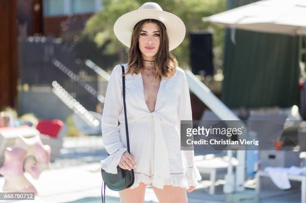 Aida Domenech wearing a white jumpsuit, bag and hat during day 1 of the 2017 Coachella Valley Music & Arts Festival Weekend 1 on April 14, 2017 in...