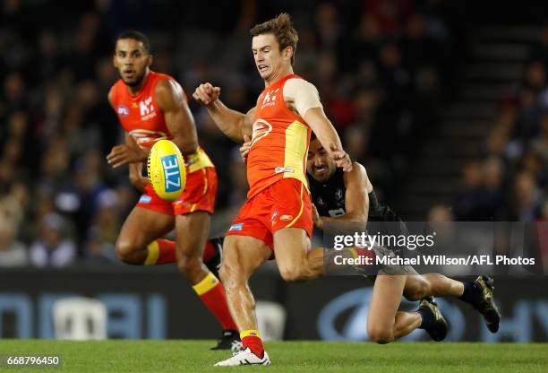 Jarryd Lyons of the Suns is tackled by Kade Simpson of the Blues during the 2017 AFL round 04 match between the Carlton Blues and the Gold Coast Suns...