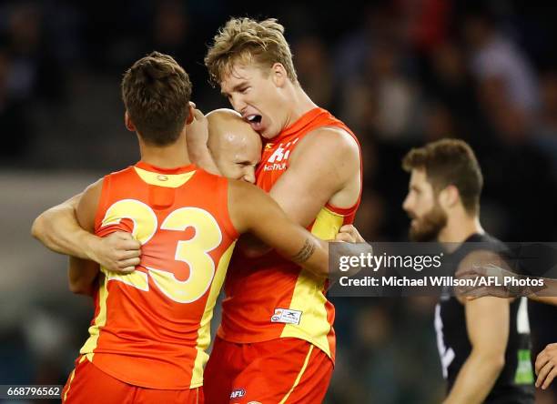 Gary Ablett of the Suns celebrates a goal with teammates Sean Lemmens and Tom Lynch during the 2017 AFL round 04 match between the Carlton Blues and...