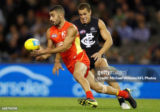 Adam Saad of the Suns is chased by Ed Curnow of the Blues during the 2017 AFL round 04 match between the Carlton Blues and the Gold Coast Suns at...