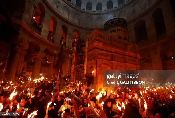 Christian Orthodox worshippers hold up candles during the ceremony of the "Holy Fire" as thousands gather in the Church of the Holy Sepulchre in...