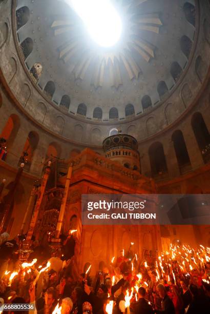 Christian Orthodox worshippers hold up candles during the ceremony of the "Holy Fire" as thousands gather in the Church of the Holy Sepulchre in...