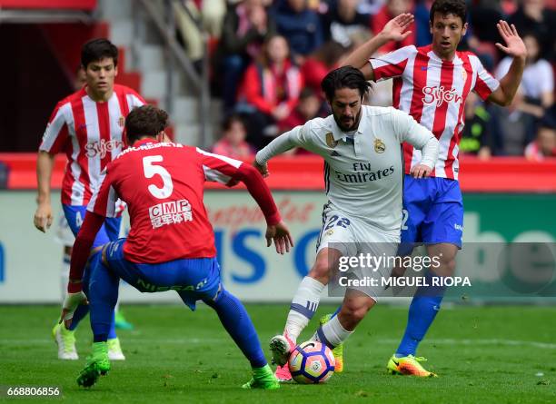 Real Madrid's midfielder Isco controls the ball next to Sporting Gijon's Venezuelan defender Fernando Amorebieta to score a goal during the Spanish...