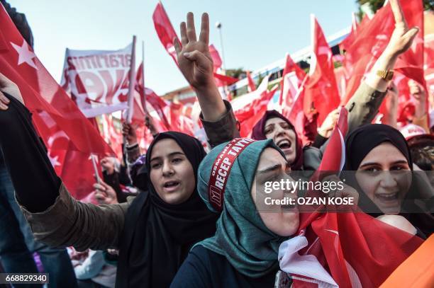 People cheer and flash a four finger sign called "the rabia sign" as the Turkish president delivers a speech in Istanbul, on April 15 during a rally...