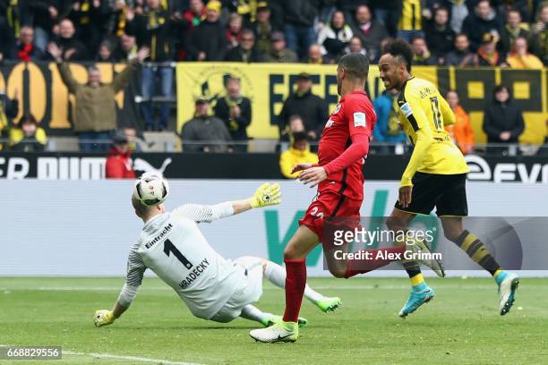 Pierre-Emerick Aubameyang of Dortmund scores his team's third goal past goalkeeper Lukas Hradecky of Frankfurt during the Bundesliga match between...