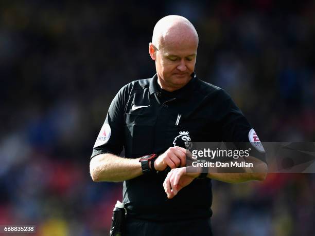 Referee Lee Mason looks at his watch during the Premier League match between Watford and Swansea City at Vicarage Road on April 15, 2017 in Watford,...