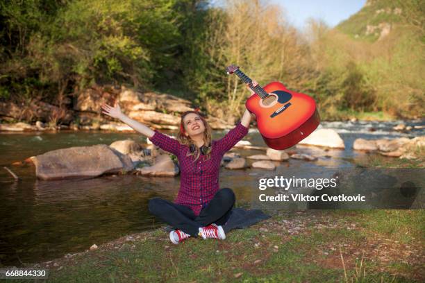 happy young woman with guitar enjoying by river - girl band stock pictures, royalty-free photos & images