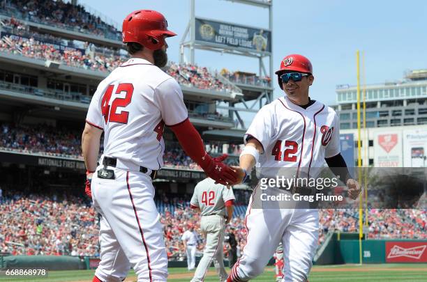 Jose Lobaton of the Washington Nationals celebrates with Bryce Harper after scoring in the third inning against the Philadelphia Phillies at...