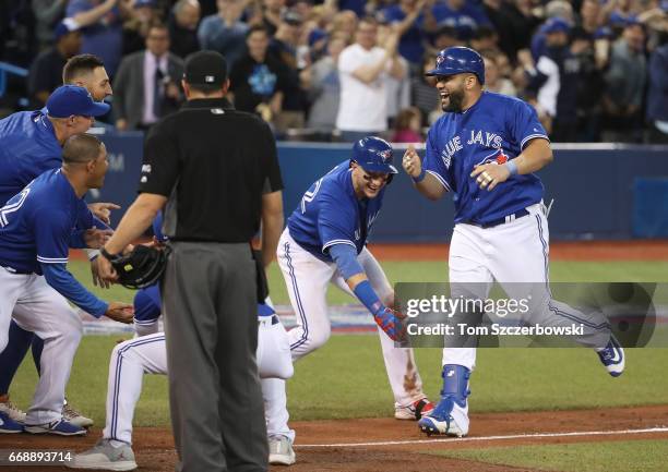 Kendrys Morales of the Toronto Blue Jays is congratulated at home plate by Troy Tulowitzki and teammates after hitting a game-winning solo home run...