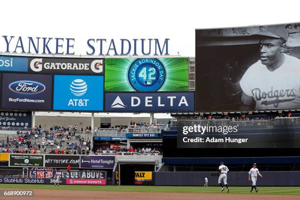 Brett Gardner of the New York Yankees and Aaron Hicks of the New York Yankees warm up as a video tribute for Jackie Robinson is played prior to...