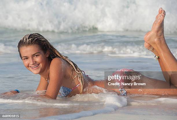 young girl with braces laying in surf bahamas. - barefoot feet up lying down girl stockfoto's en -beelden