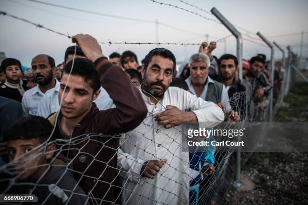 Men listen for their names to be called out by a camp official overseeing the return of refugees to recaptured parts of Mosul on April 15, 2017 near...
