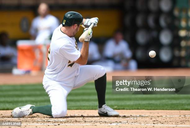 Adam Rosales of the Oakland Athletics squeeze bunts to score Yonder Alonso against the Houston Astros in the bottom of the second inning at Oakland...