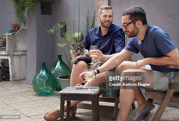 two men enjoying drinks on their terrace - only mid adult men stock pictures, royalty-free photos & images