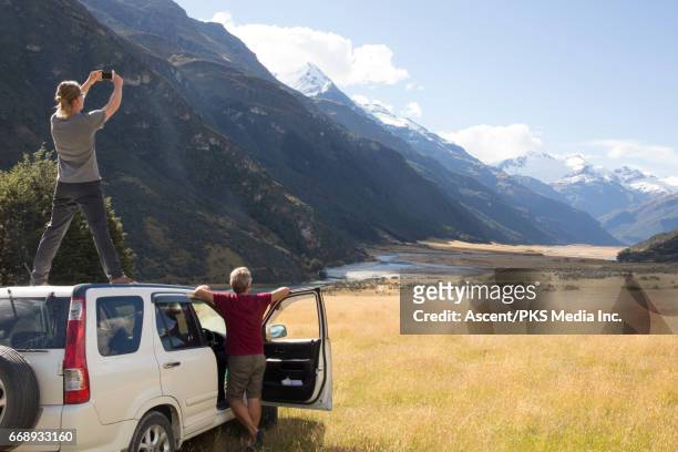 two men take smart phone pic from off road vehicle - queenstown stock pictures, royalty-free photos & images