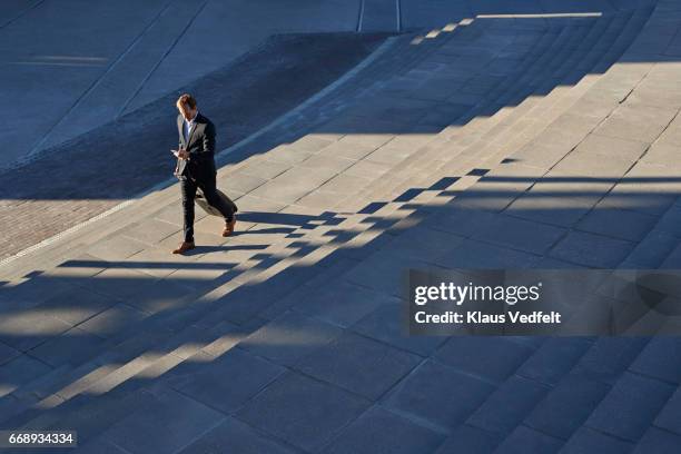 businessman walking on outside staircase and looking at phone - business people sunrise walking through the city stock pictures, royalty-free photos & images