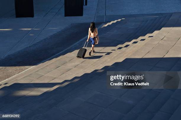 businesswoman walking on outside staircase with suitcase and looking at phone - carry on luggage photos et images de collection
