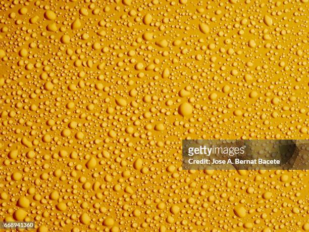 full frame of the textures formed by the bubbles and drops, on a smooth yellow background - frescura stock-fotos und bilder