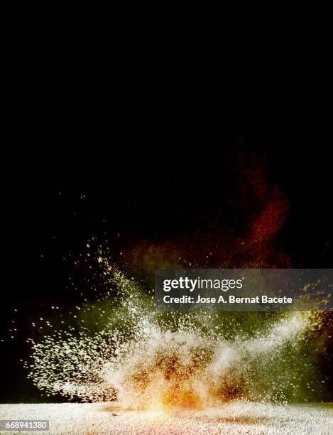 explosion of a cloud of powder of particles of yellow and red color on a black background - caer stock-fotos und bilder